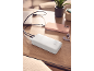 Λευκό power bank φορτίζει ένα ροζ smartphone και ένα laptop σε ξύλινο τραπέζι.