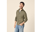 Άντρας με χαμόγελο, φορώντας πράσινη ζακέτα με φερμουάρ και τζιν.