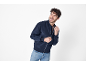 Χαμογελαστός άνδρας με σκούρο μπλε bomber jacket και τζιν.