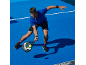 Άνδρας με αθλητική ενδυμασία παίζει padel σε μπλε γήπεδο.