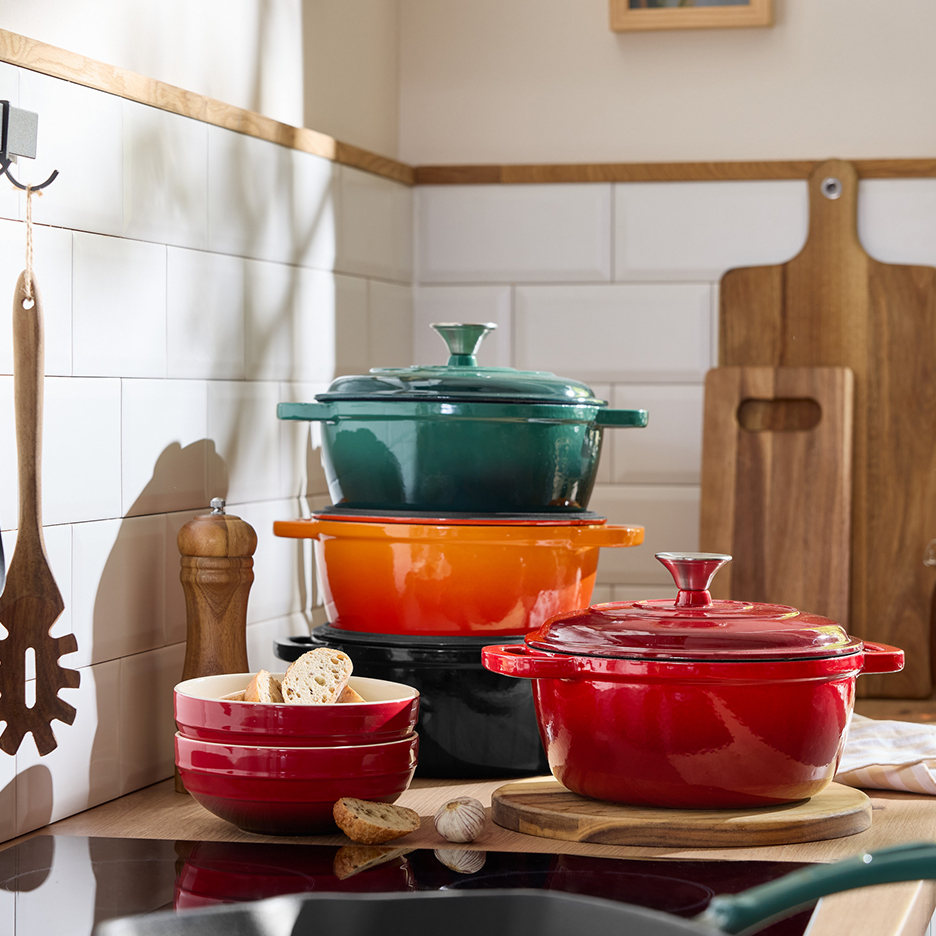 Μια συλλογή από πολύχρωμα εμαγιέ σκεύη από χυτοσίδηρο, μπολ και μαγειρικά σκεύη.