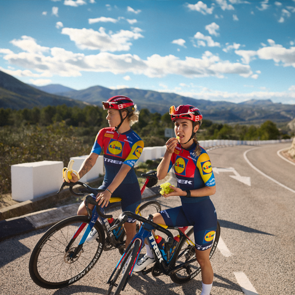 Δύο ποδηλάτισσες της ομάδας Trek-Segafredo Lidl απολαμβάνουν ένα διάλειμμα με φρούτα.