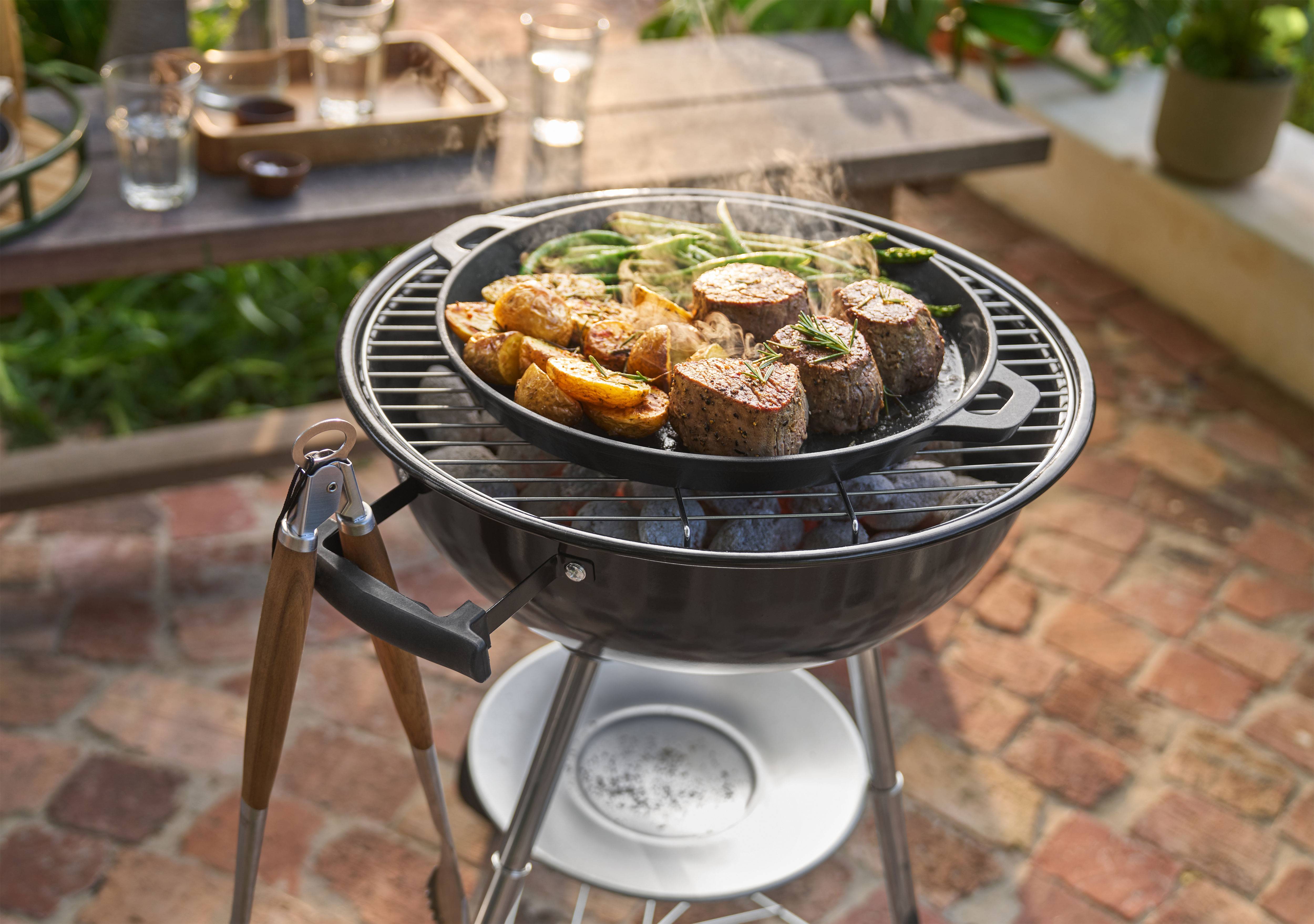 Μπάρμπεκιου με κρέας, πατάτες και πράσινα φασόλια να ψήνονται σε τηγάνι σε εξωτερικό χώρο.