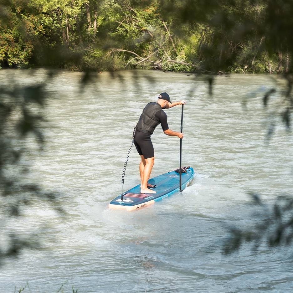 Άνδρας με στολή και σωσίβιο κάνει paddleboard σε μπλε σανίδα σε ποτάμι.