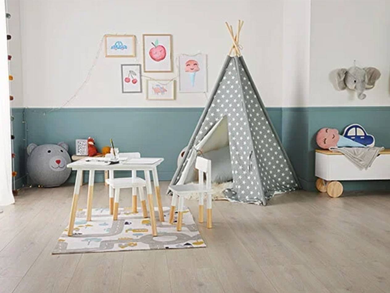 Παιδικό δωμάτιο με σκηνή tipi, τραπέζι και καρέκλες, μπαούλο παιχνιδιών και εικόνες στον τοίχο.
