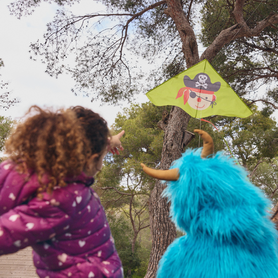 Παιδί και μπλε τέρας κοιτούν έναν χαρταετό με πειρατή που έχει κολλήσει σε δέντρο.