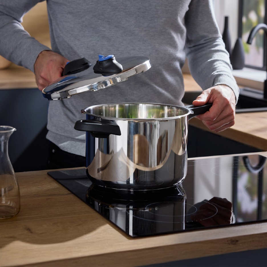 Άνδρας τοποθετεί καπάκι σε χύτρα ταχύτητας πάνω σε επαγωγική εστία.