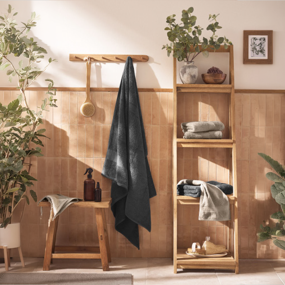 Μπάνιο με ξύλινα ράφια, πετσέτες, φυτά και αξεσουάρ μπάνιου.
