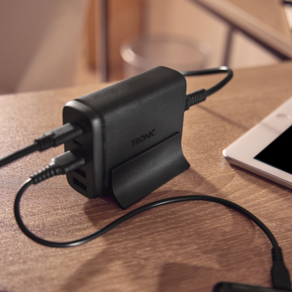 Μαύρος επιτραπέζιος φορτιστής USB με συνδεδεμένα καλώδια πάνω σε ξύλινο γραφείο.