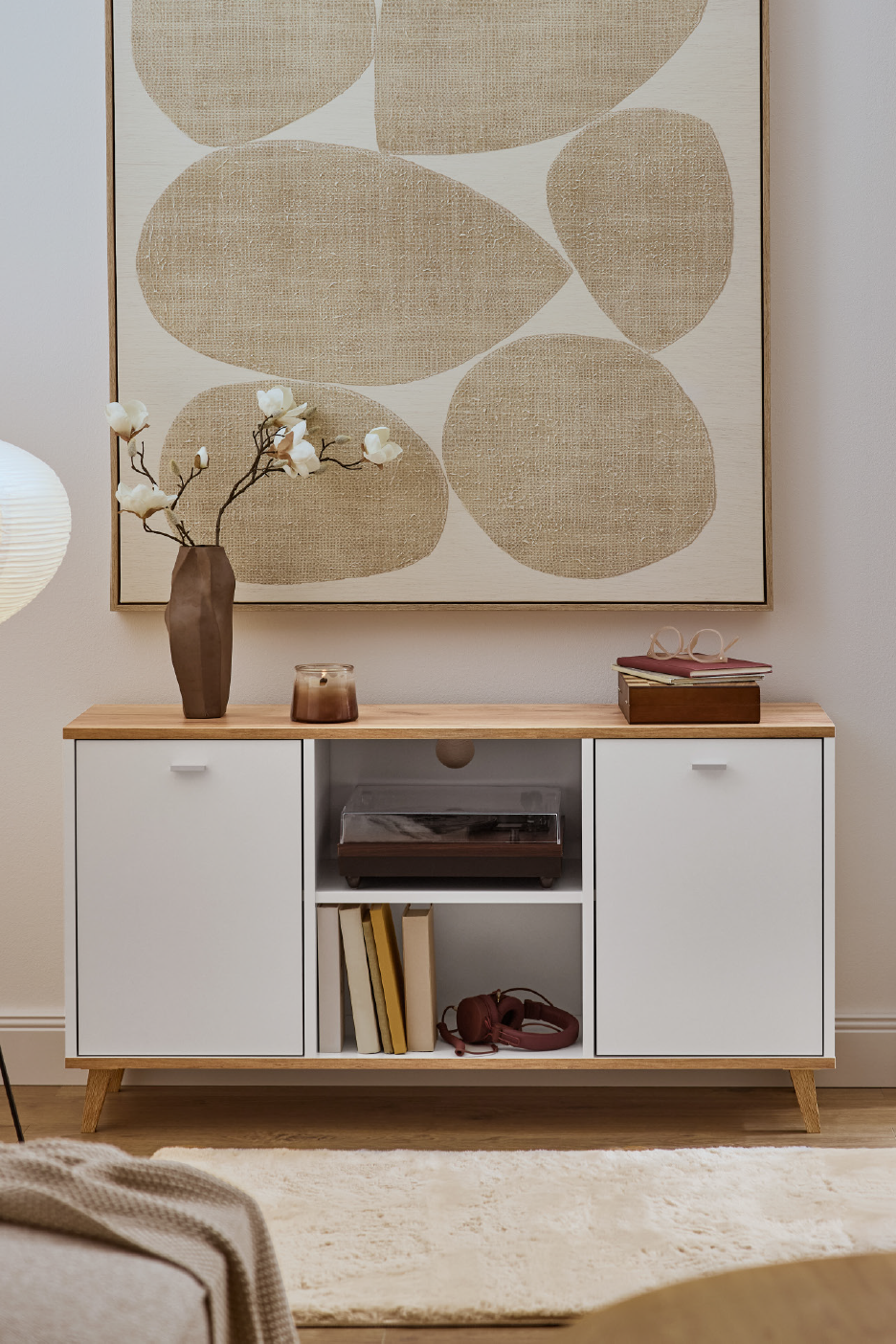 Λευκό έπιπλο τηλεόρασης με ξύλινη επιφάνεια, διακοσμημένο με βάζο, κερί και πικάπ.
