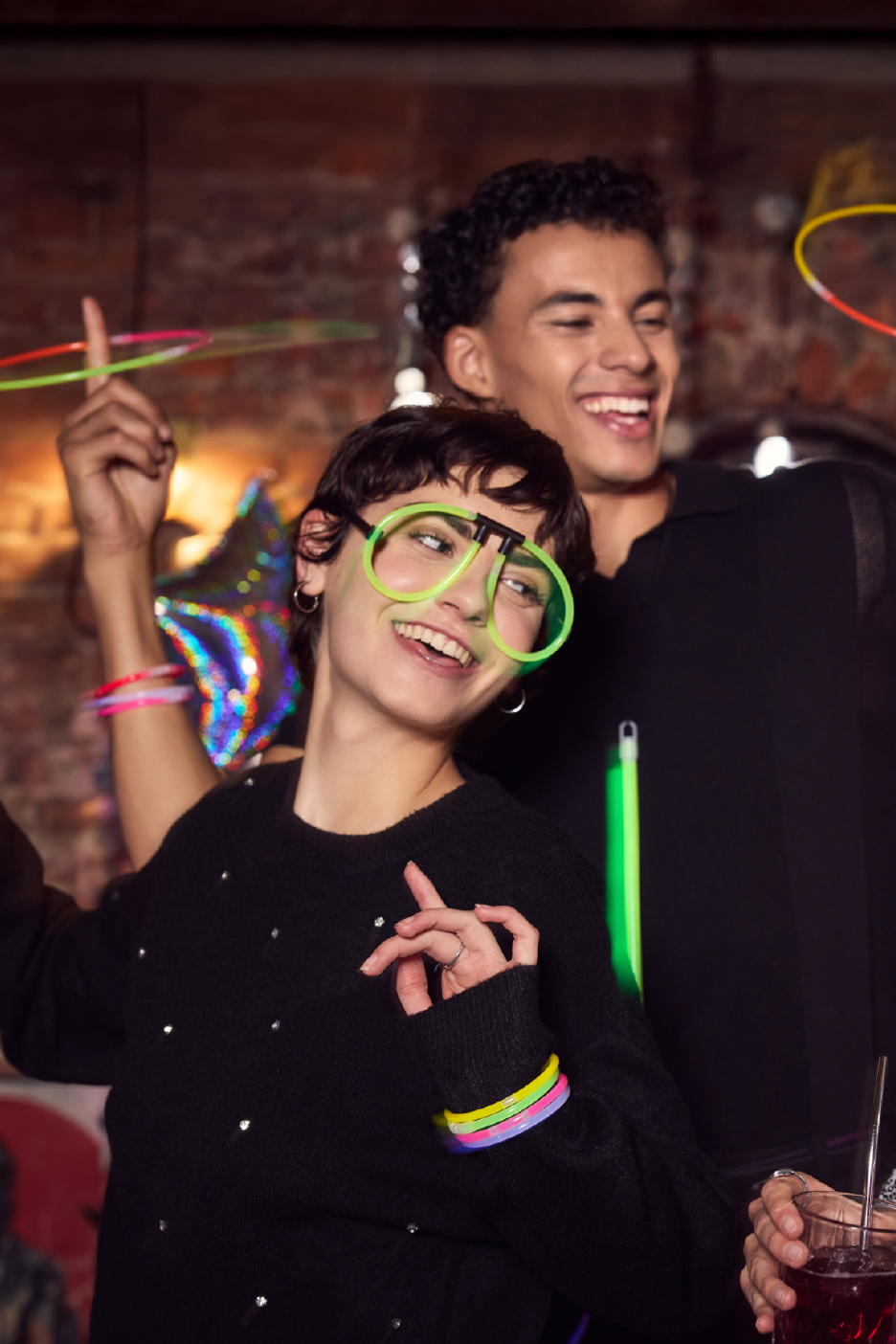 Δύο χαρούμενοι νέοι σε ένα πάρτι, με φωσφοριζέ γυαλιά και βραχιόλια.