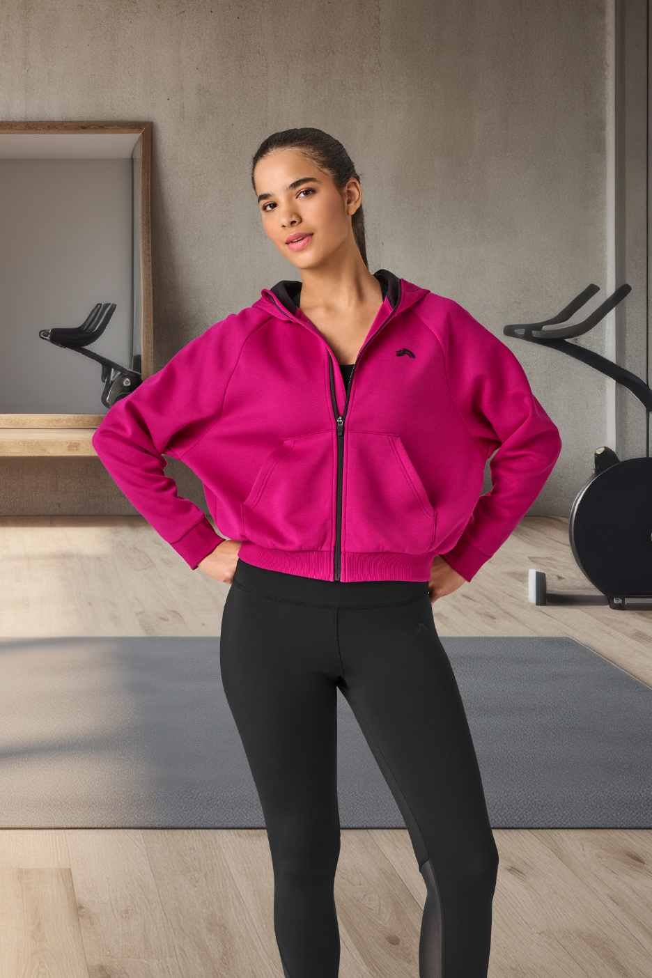 Γυναίκα με φούξια ζακέτα και μαύρο κολάν σε γυμναστήριο.