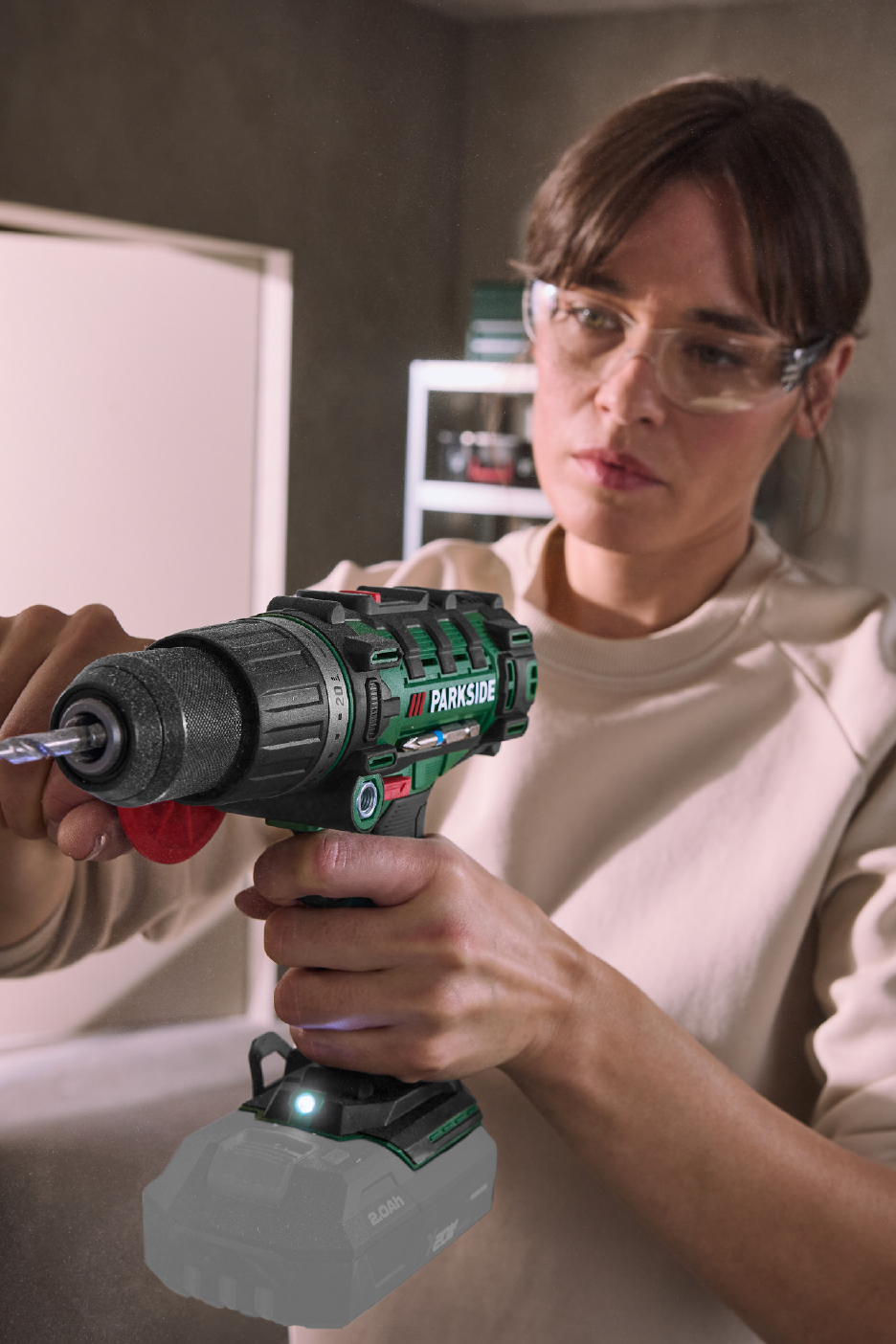 Γυναίκα με γυαλιά ασφαλείας χρησιμοποιεί ένα ασύρματο δράπανο.