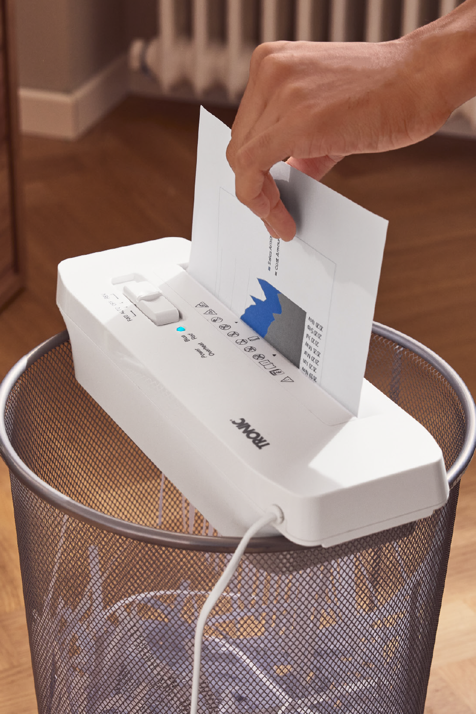 Ένα άτομο χρησιμοποιεί έναν καταστροφέα εγγράφων που βρίσκεται πάνω σε έναν μεταλλικό κάδο απορριμμάτων.