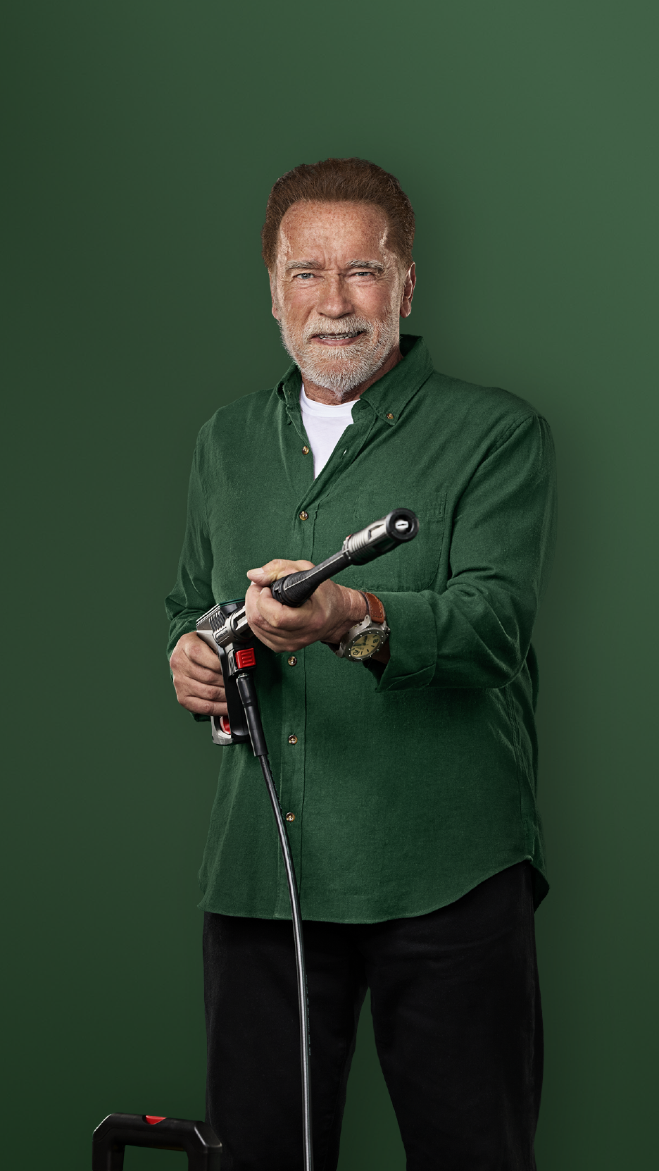 Ο Άρνολντ Σβαρτσενέγκερ κρατάει ένα πλυστικό μηχάνημα πίεσης, χαμογελώντας.