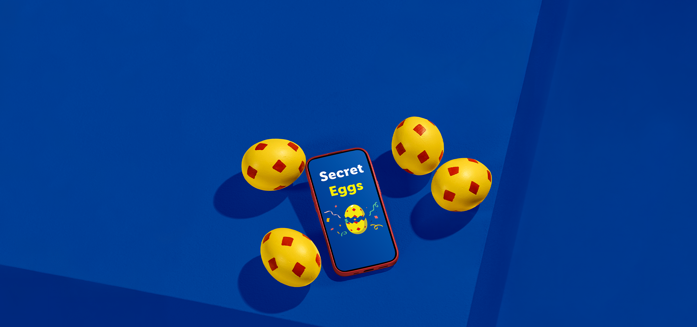 Κίτρινα αυγά με κόκκινα τετράγωνα και ένα smartphone με την επιγραφή «Secret Eggs» σε μπλε φόντο.