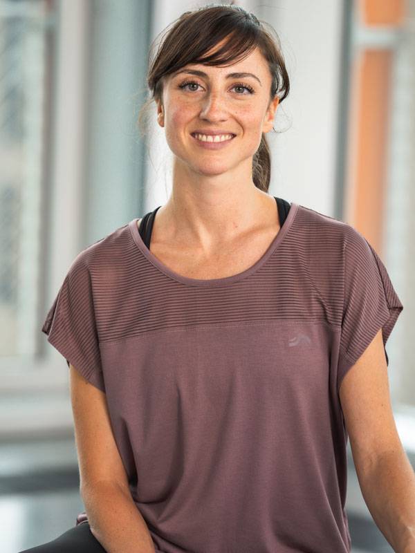 Χαμογελαστή γυναίκα με κοντομάνικο μωβ αθλητικό τοπ.