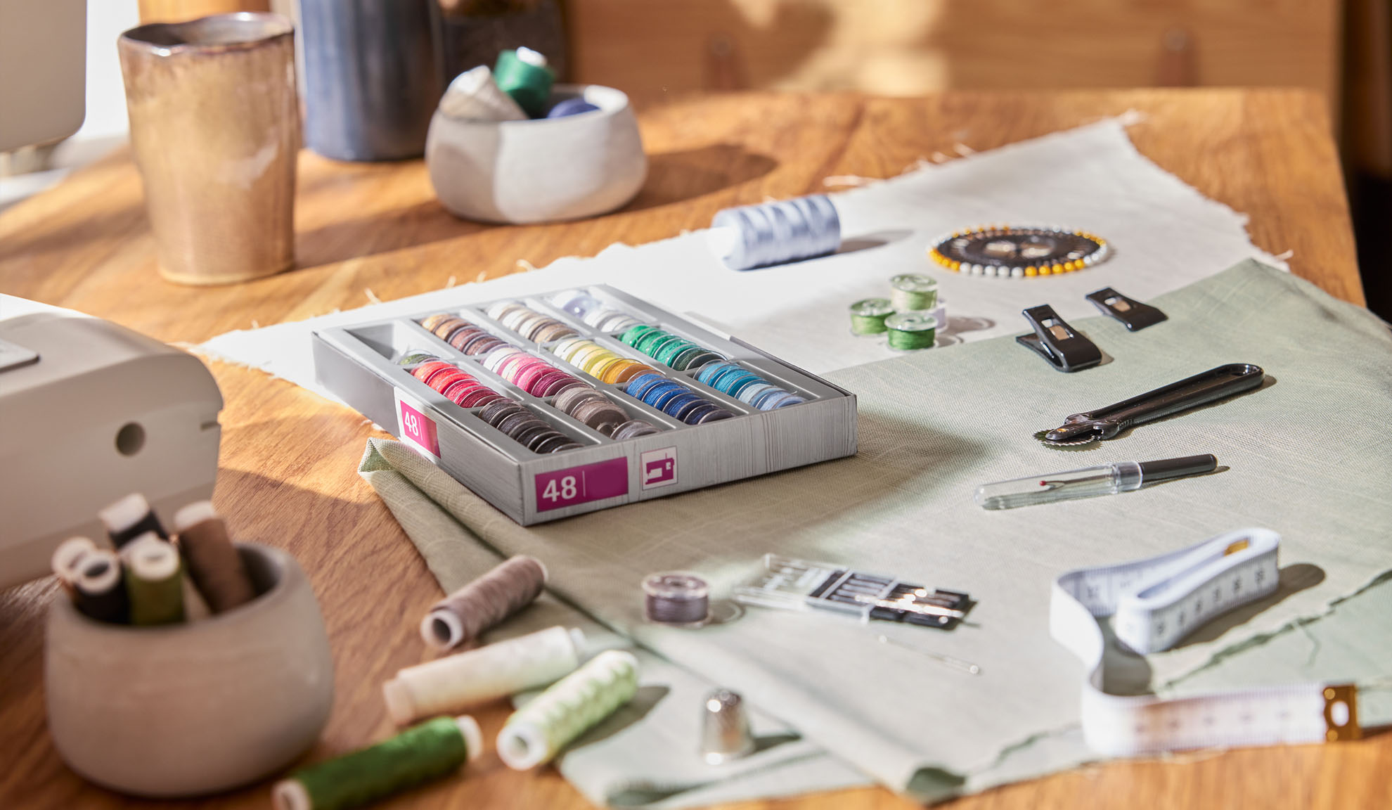 Σετ ραπτικής με κουτί πολύχρωμων κλωστών, ραπτομηχανή και διάφορα εργαλεία σε ξύλινο τραπέζι.