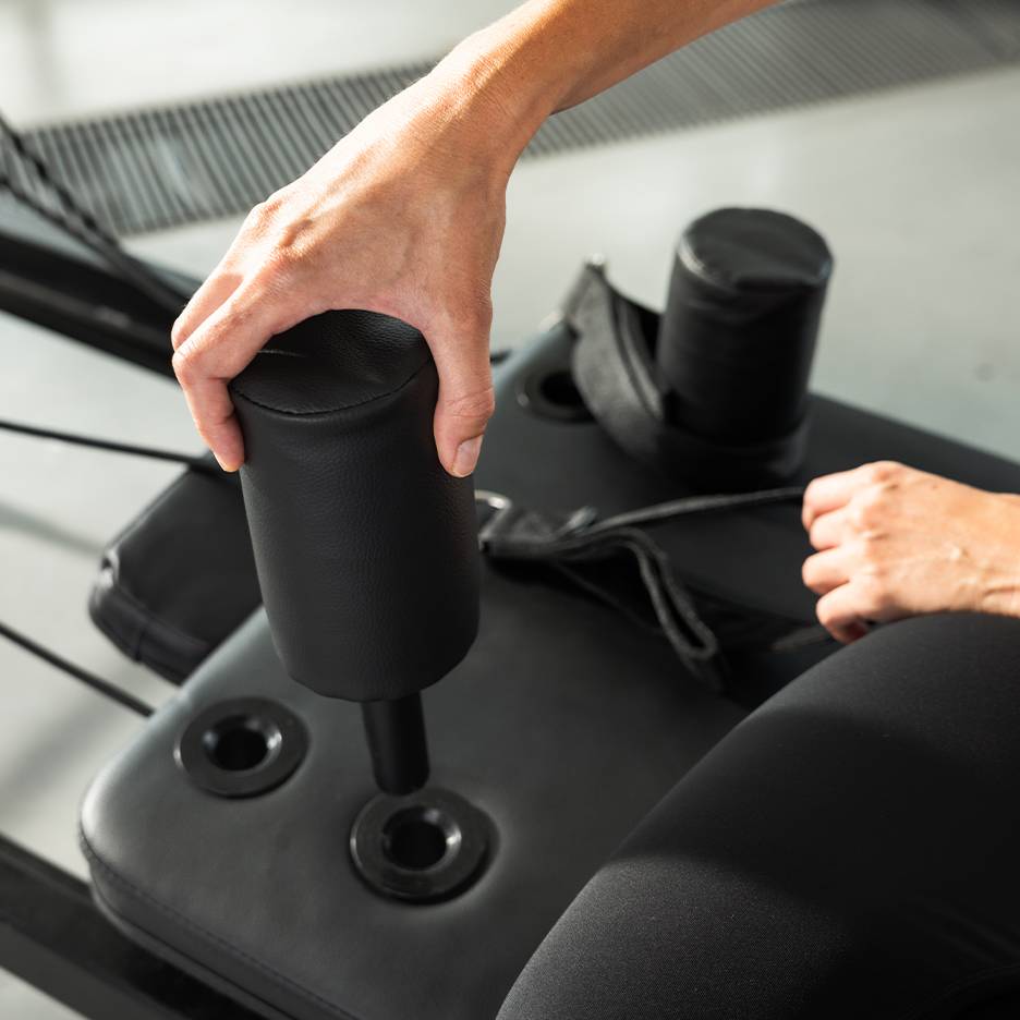 Άτομο που ρυθμίζει ένα μαύρο επενδυμένο όργανο γυμναστικής.