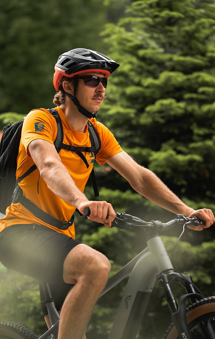Άνδρας οδηγεί mountain bike με κράνος και αθλητικά ρούχα.