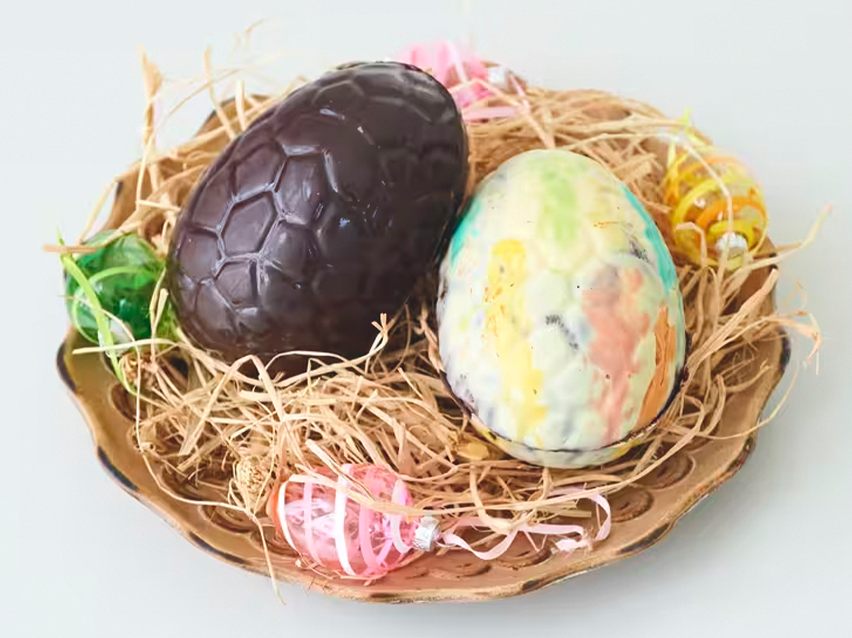 Σοκολατένια πασχαλινά αυγά σε φωλιά από άχυρο, με διακοσμητικά αυγά.