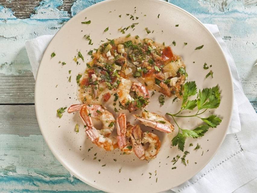 Γαρίδες και ψάρι με σάλτσα από βότανα και λαχανικά σε πιάτο.