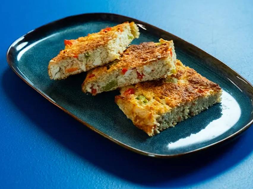 Τρία κομμάτια ομελέτας με λαχανικά σε ένα μπλε πιάτο.