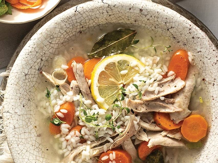 Κοτόσουπα με ρύζι, καρότα, λεμόνι και μυρωδικά σε ρουστίκ μπολ.