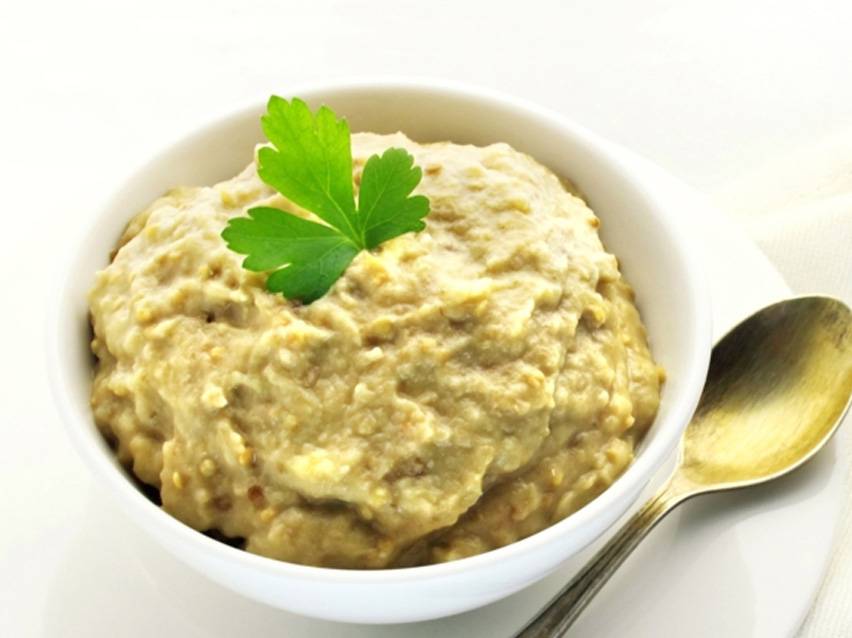 Μπάμπα γκανούς σε λευκό μπολ με μαϊντανό και κουτάλι.