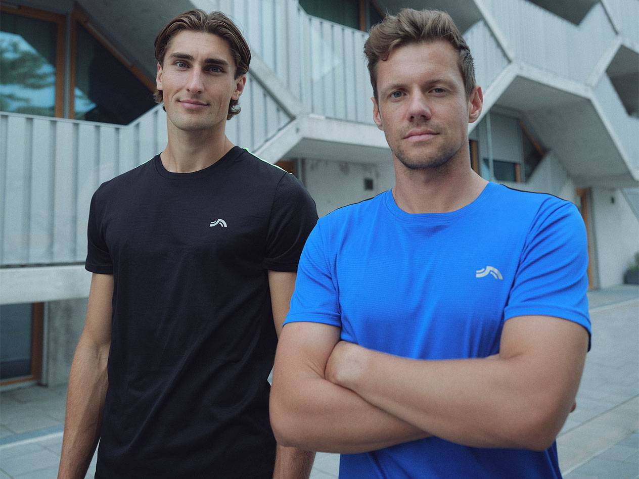 Δύο άνδρες με μαύρα και μπλε αθλητικά μπλουζάκια με λογότυπο.