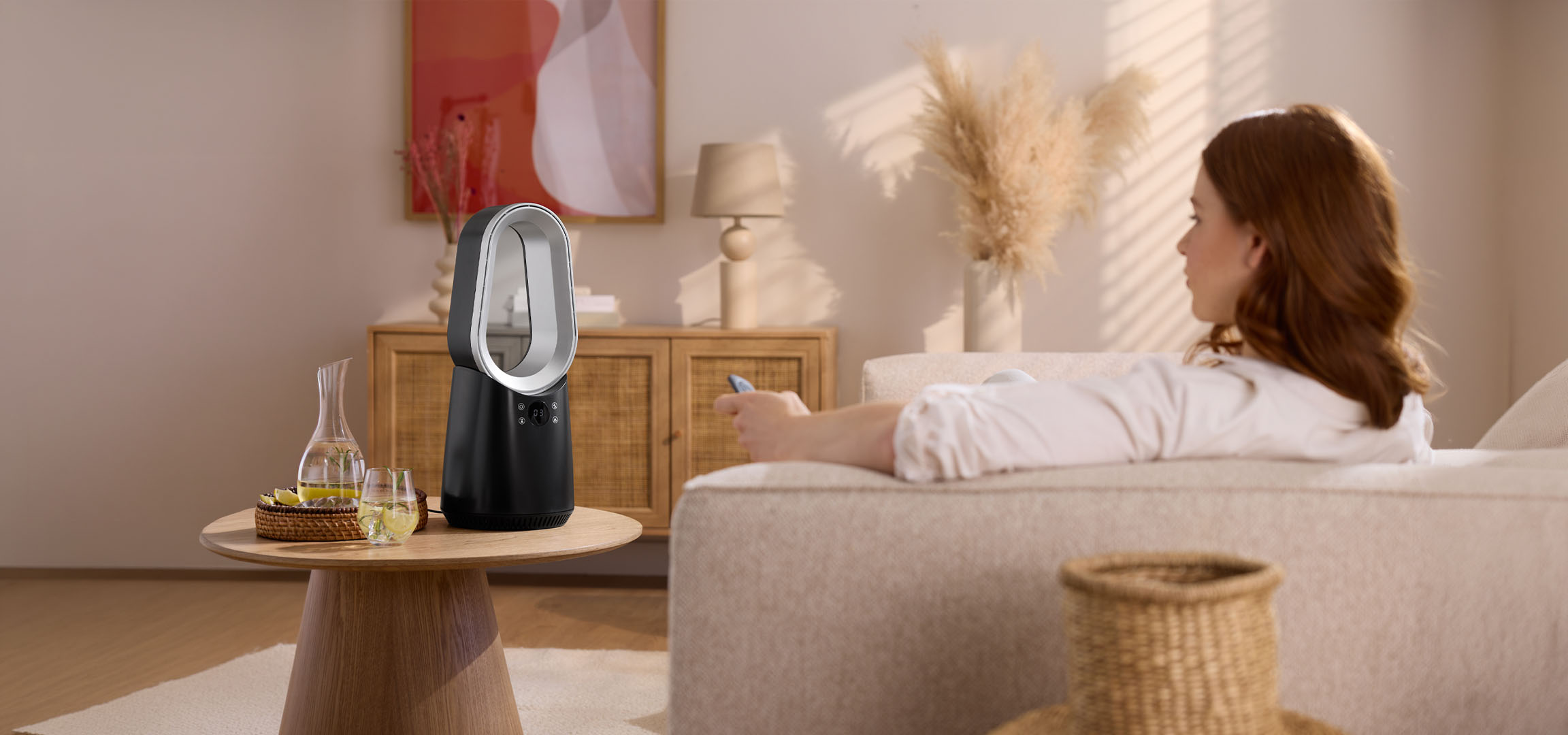 Γυναίκα σε καναπέ με τηλεχειριστήριο, μοντέρνος ανεμιστήρας και ποτά στο τραπέζι.