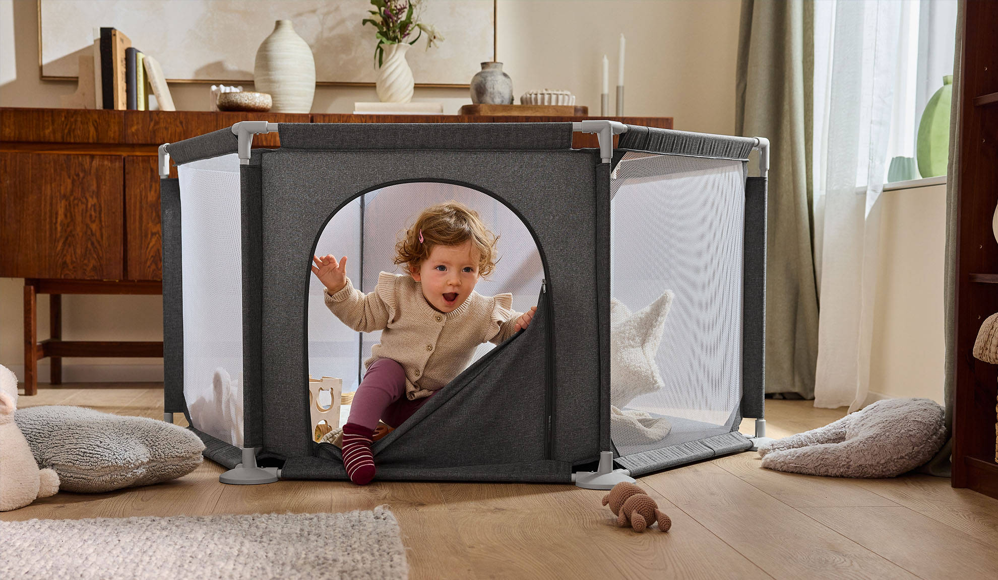 Ευτυχισμένο μωρό βγαίνει από ένα γκρι πάρκο σε ένα ζεστό σαλόνι.