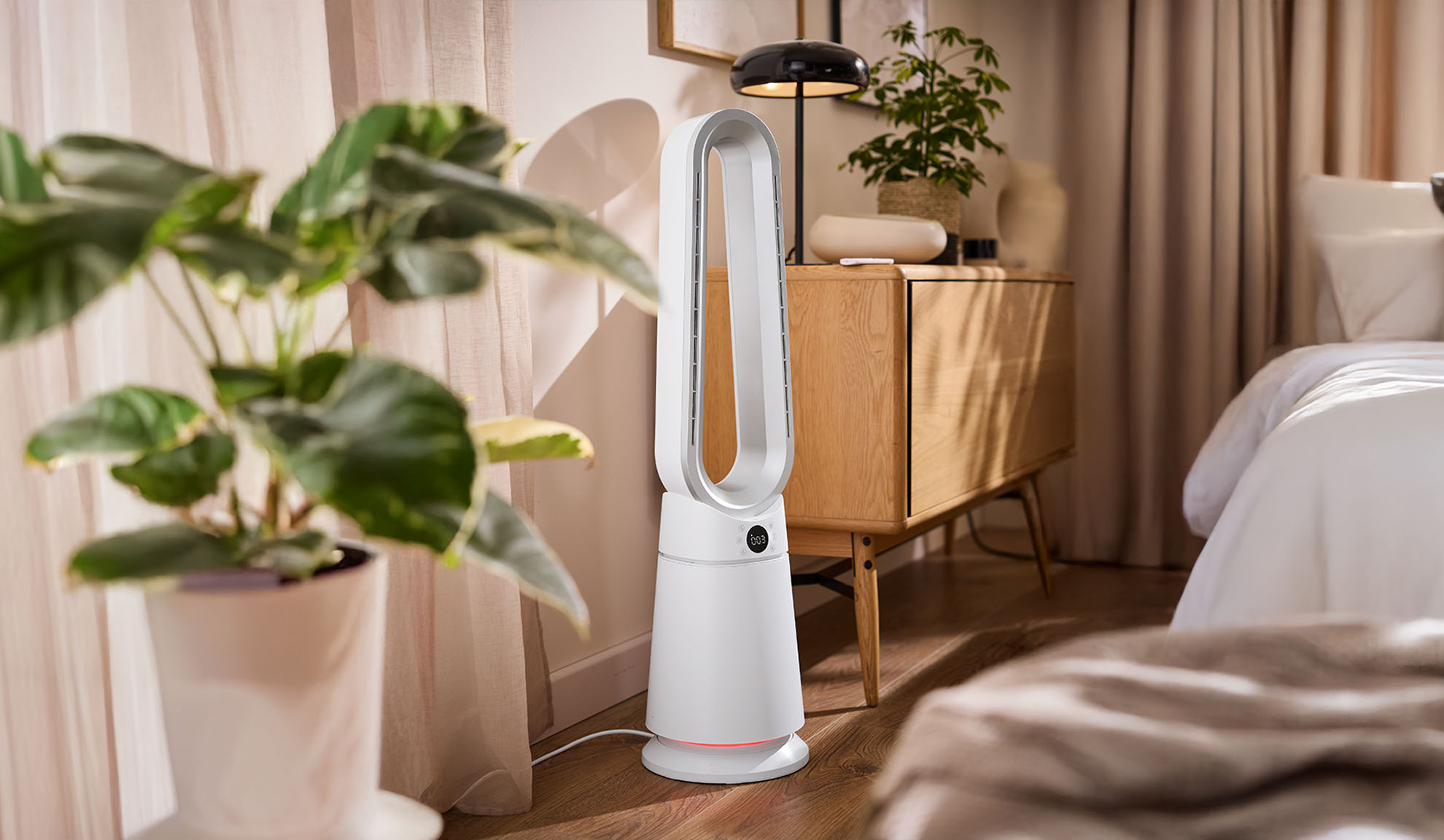 Λευκός ανεμιστήρας πύργου σε ένα μοντέρνο υπνοδωμάτιο με φυτά και ξύλινα έπιπλα.