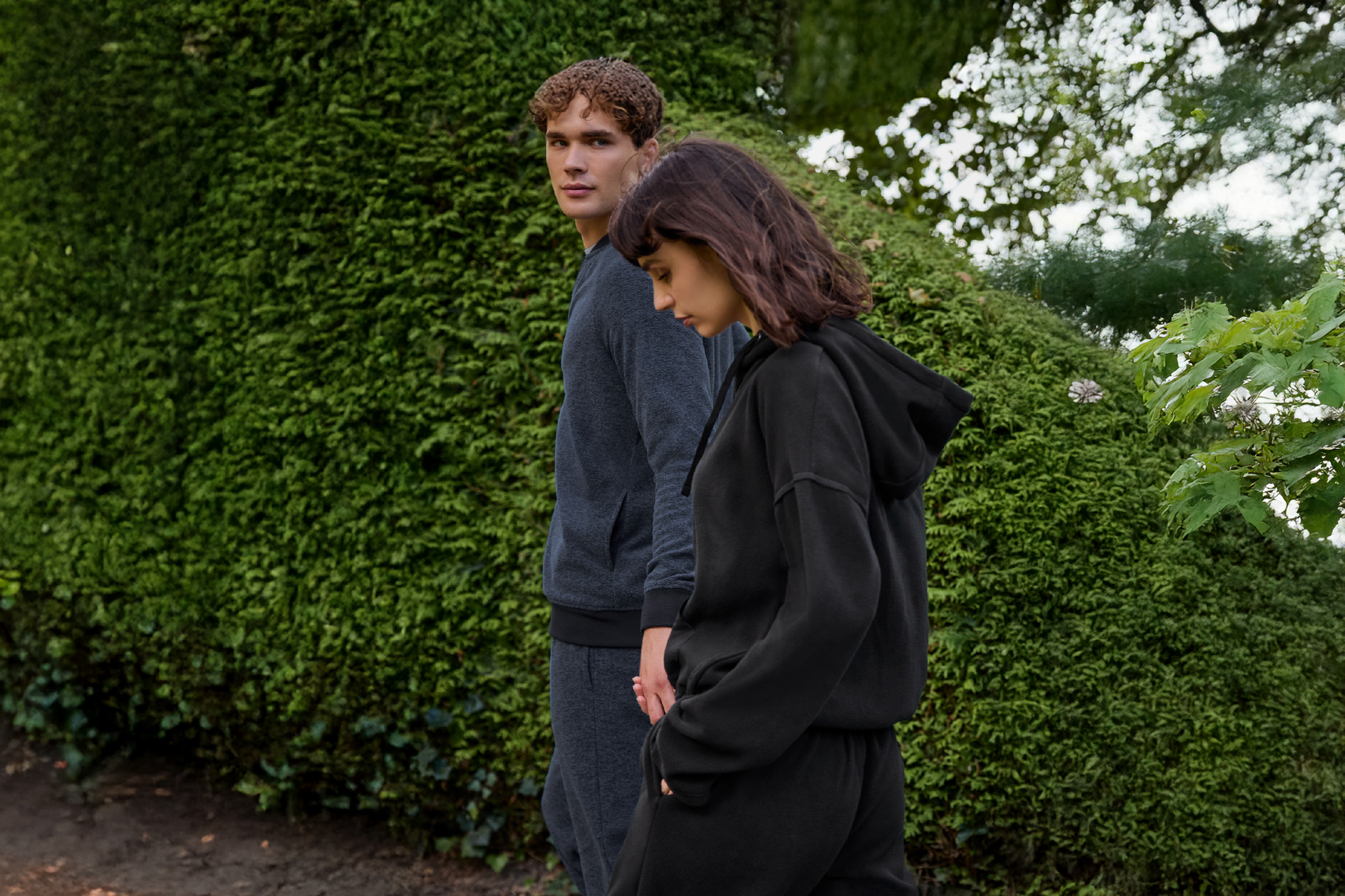 Ένα ζευγάρι περπατάει φορώντας ασορτί αθλητικές φόρμες, ο άντρας κοιτάζει την κάμερα.