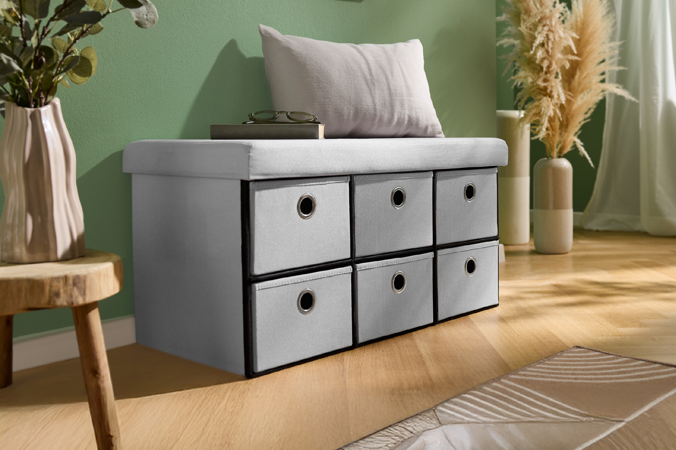 Πάγκος αποθήκευσης με έξι συρτάρια, μαξιλάρι και διακοσμητικά φυτά σε πράσινο δωμάτιο.