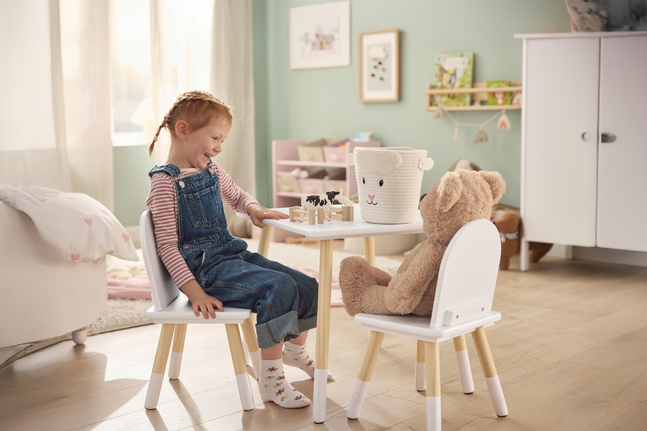 Παιδικό τραπέζι και καρέκλες με κορίτσι και αρκουδάκι να παίζουν με παιχνίδια αγροκτήματος.