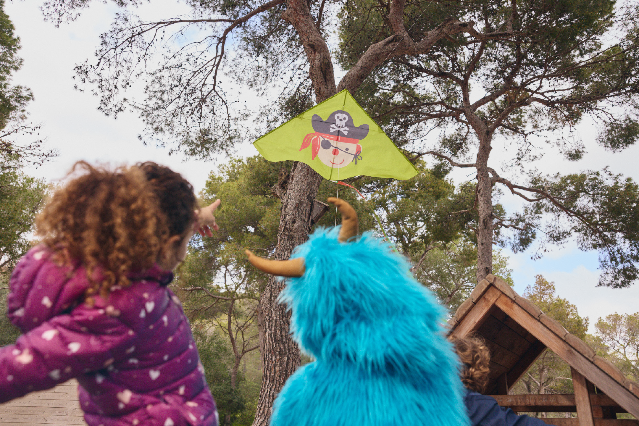 Παιδιά κοιτάζουν έναν χαρταετό με πειρατή που έχει κολλήσει σε ένα δέντρο.