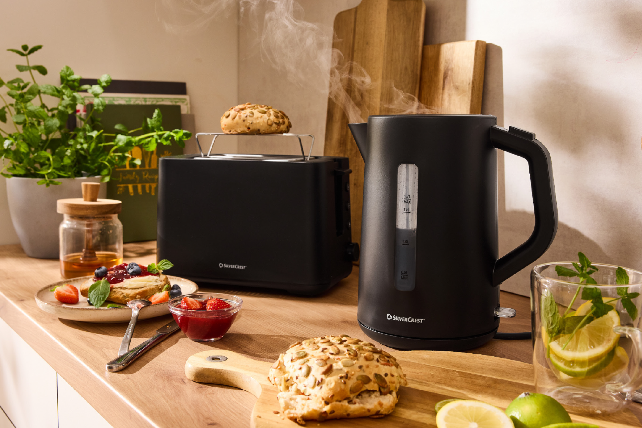 Μαύρος βραστήρας και φρυγανιέρα σε ξύλινο πάγκο με πρωινό και ζεστό ρόφημα.