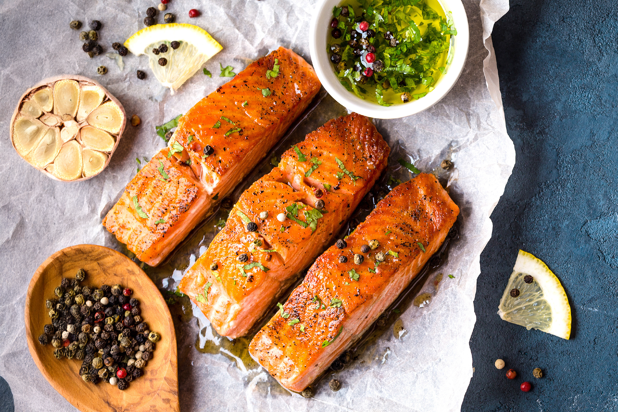 Τρία φιλέτα σολομού με βότανα, σκόρδο, πιπέρι και λεμόνι σε λαδόκολλα.