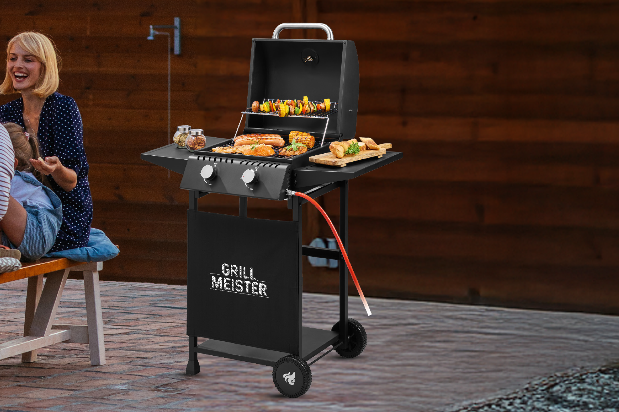 Μαύρη ψησταριά αερίου με φαγητό και γυναίκα να γελάει σε εξωτερικό χώρο.