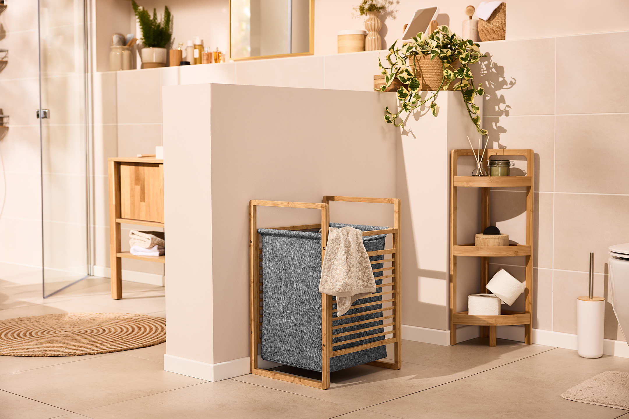 Μπάνιο με καλάθι απλύτων από μπαμπού, ράφι και ξύλινο ντουλάπι.