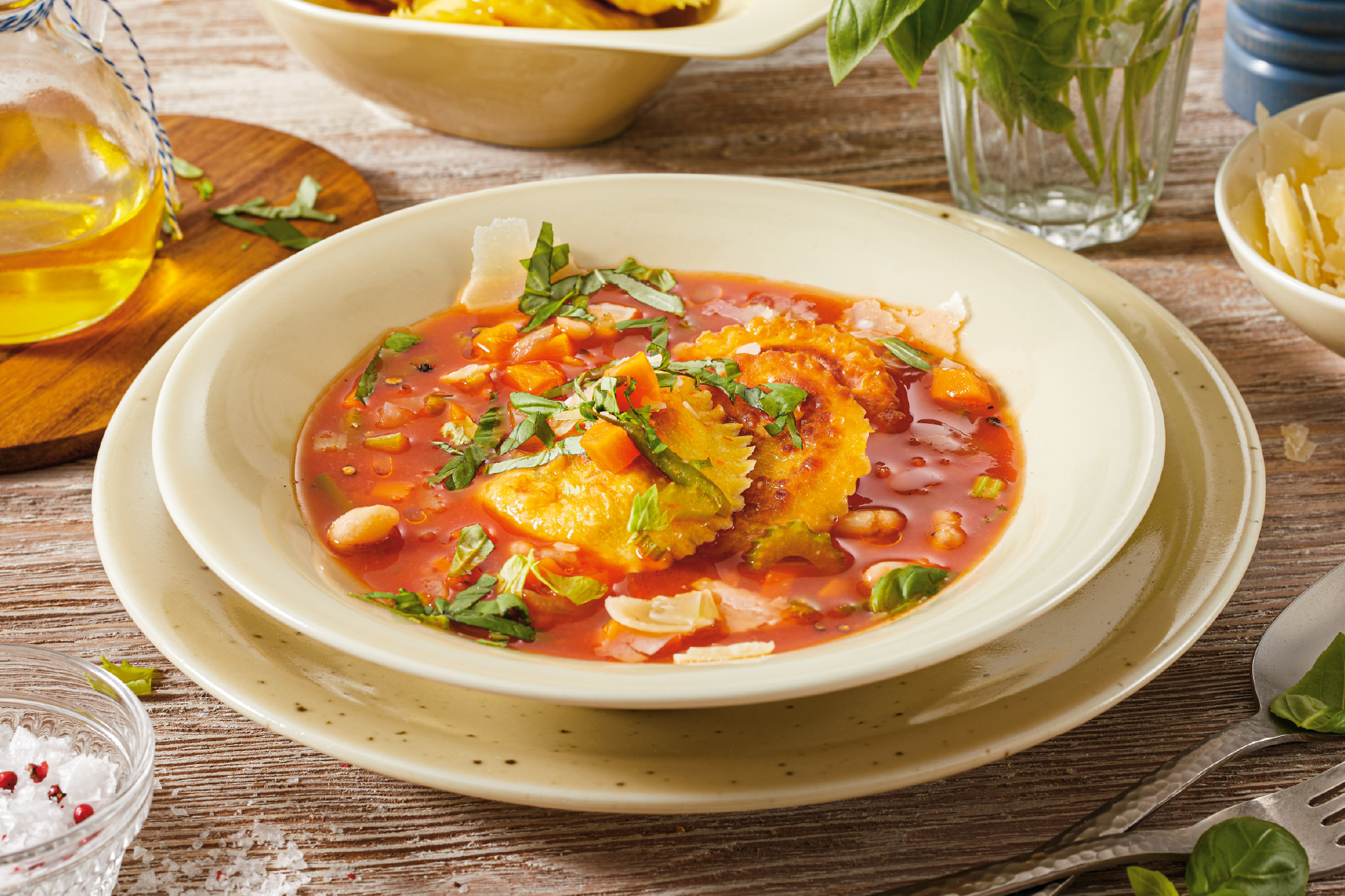 Ραβιόλια σε κόκκινη σάλτσα με λαχανικά, παρμεζάνα και βασιλικό, με λάδι και αλάτι στο πλάι.