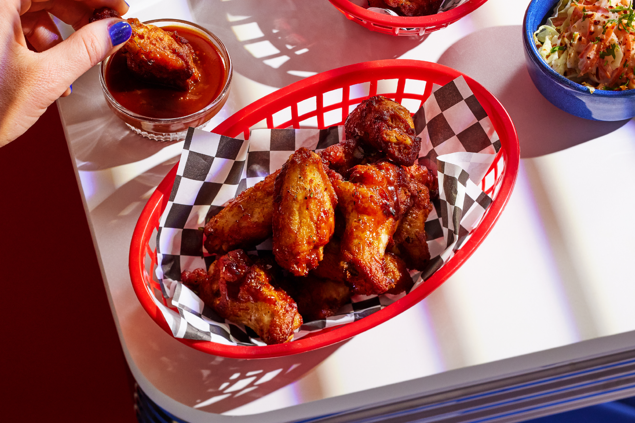 Κοτόπουλο φτερούγες με σάλτσα και λάχανο σαλάτα σε ένα τραπέζι