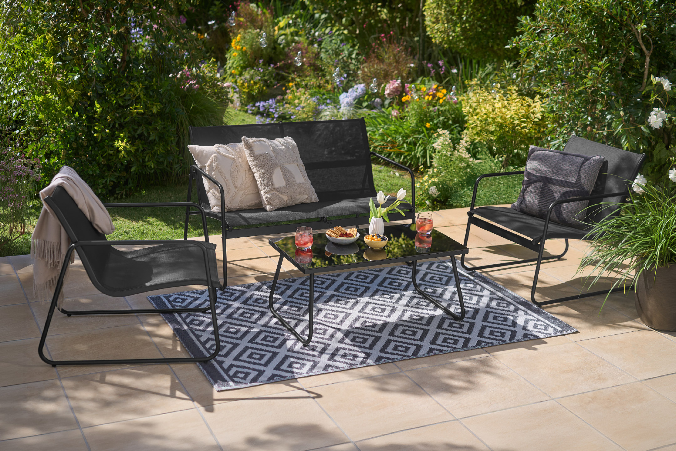 Σετ επίπλων κήπου με τραπέζι, καρέκλες και διθέσιο καναπέ, με χαλί εξωτερικού χώρου.
