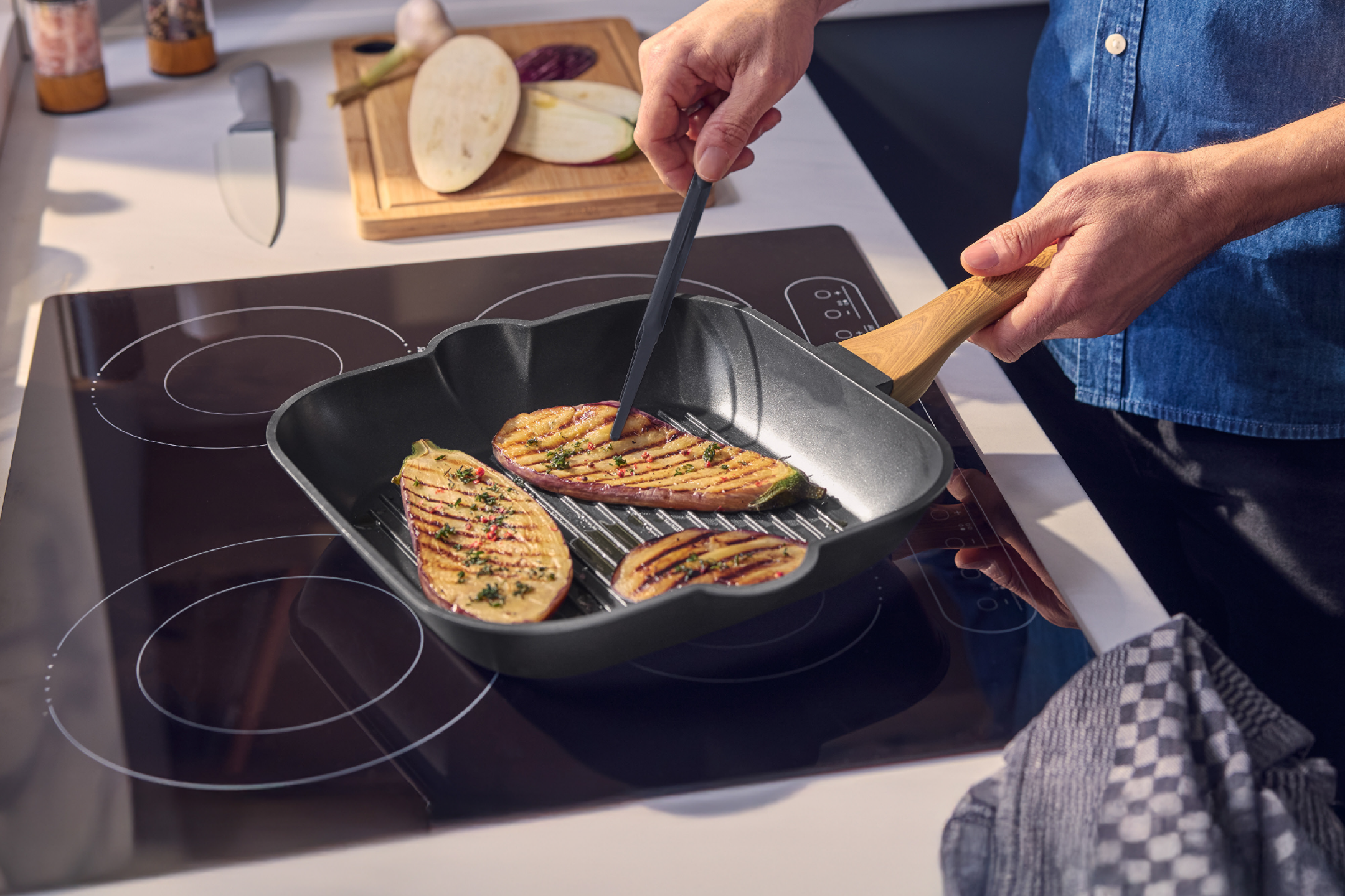 Άνδρας ψήνει μελιτζάνες σε αντικολλητικό τηγάνι-γκριλ σε επαγωγική εστία.