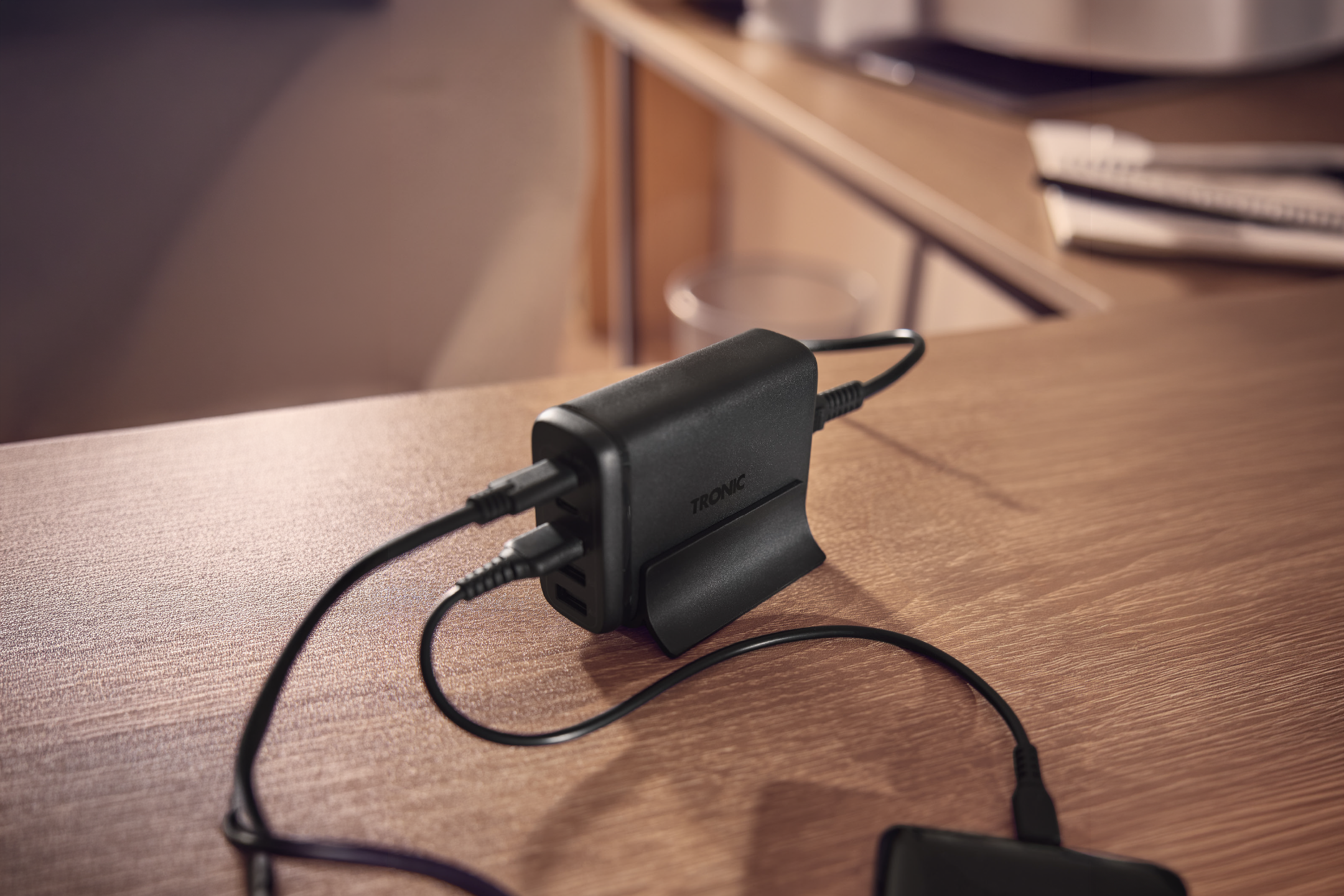 Μαύρος επιτραπέζιος φορτιστής USB με συνδεδεμένα καλώδια πάνω σε ξύλινο γραφείο.